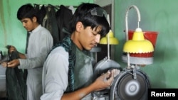 An Afghan youth checks on a piece of blue lapis lazuli that he is cutting at a gem cutting school in Kunduz.