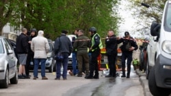 Поліцейські стоять поруч із тілами на місці стрілянини в Києві, 18 квітня 2026 року