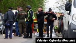 Поліцейські стоять поруч із тілами на місці стрілянини в Києві, 18 квітня 2026 року