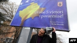 Un etnic albanez în faţa unui billboard cu inscripţia "La Mulţi Ani Kosovo, cu ocazia celei de a cincea aniversări a independenţei", la Pristina, 13 februarie 2013