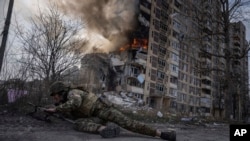 A Ukrainian police officer takes cover in front of a burning building that was hit by a Russian air strike in Avdiyivka, Ukraine, on March 17.