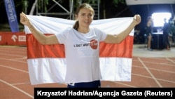 Krystsina Tsimanouskaya poses for a picture with a red and white flag, which is a symbol of the opposition movement in Belarus, during a competition at a stadium in Szczec, Poland, in August 2021.
