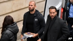 Andrew Tate (center) and his brother, Tristan (right), are brought by police officers to an appeals court in Bucharest on January 10. 