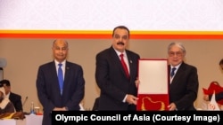 حفیظ‌الله ولی رحیمی، رئیس کمیتۀ ملی المپیک افغانستان در تبعید در حال دریافت جایزۀ "لیاقت" شورای المپیک آسیا