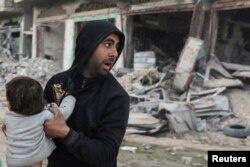  Палестинец носи ранено дете след израелски удар в Бейт Лахия в северната част на Ивицата Газа, 19 март 