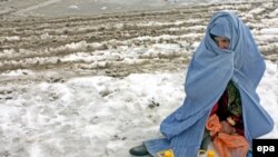 Afghanistan -- A woman waits for transport after receiving relief goods at a distribution  center in Kabul, 08Feb2010