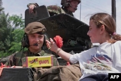 Një vajzë i jep një lule një ushtari britanik në Prishtinë më 13 qershor 1999.