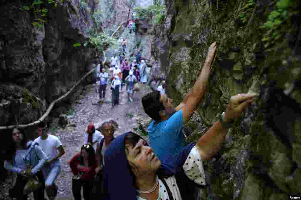 A Bosnian Muslim woman breaks off a piece of rock for good luck before commemorating the anniversary of Ajvatovica near the village of Prusac in Bosnia-Herzegovina. Ajvatovica is the largest traditional religious and cultural event of Bosniaks. (Reuters/Dado Ruvic)