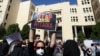 An Iranian woman, hiding her face so as not to be identified, raises a placard during a protest to show solidarity with the acid-attack victims, in front of the judiciary building in Isfahan on October 22.