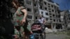 Місцеві жителі виносять свої речі з сильно пошкодженого житлового будинку після російського удару в місті Білозерське Донецької області 12 серпня 2025 року