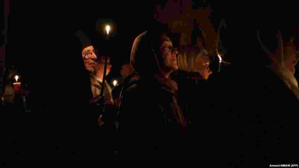 Pravoslavna vjernica se moli, dok drugi drže upaljene svijeće tokom bogosluženja u manastiru Gračanica na Kosovu.