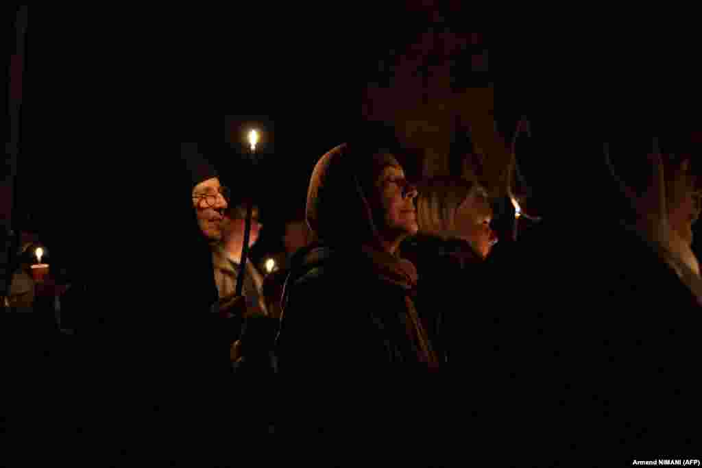 Një besimtare ortodokse lutet, teksa të tjerë mbajnë në duar qirinj të ndezur në meshën në manastirin e Graçanicës në Kosovë.