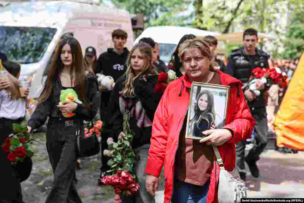 Однокласники та класна керівниця несуть квіти та іграшки до зруйнованої багатоповерхівки, де загинула 15-річна Марія