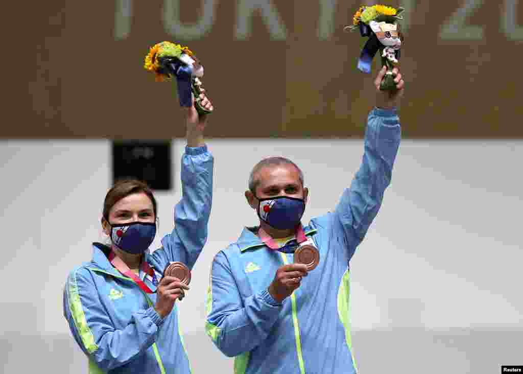 Бронзовые призеры из Украины Елена Костевич и Олег Омельчук празднуют на трибуне. Смешанная команда взяла бронзу в соревновании по стрельбе с 10 метров из пневматического пистолета