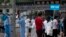 CHINA -- Medical staff in full protective gear carry signs to assist people who live near or who have visited the Xinfadi Market, a wholesale food market where a new COVID-19 coronavirus cluster has emerged, as they arrive for testing in Beijing on June 1