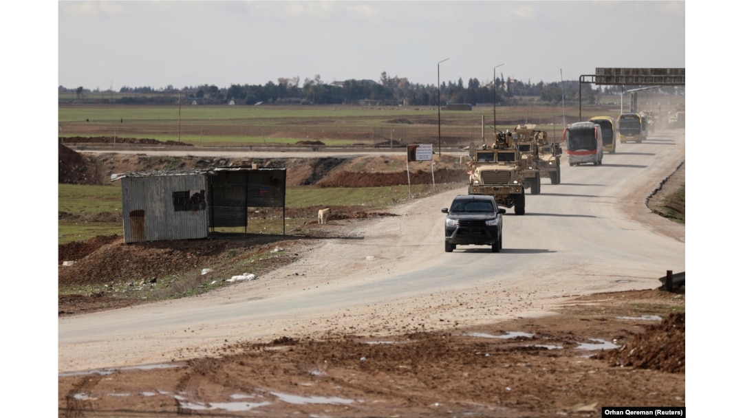 Američka vojna vozila kreću se ispred autobusa koji prevoze pritvorenike "Islamske države" iz Sirije u Irak, februar 2026.