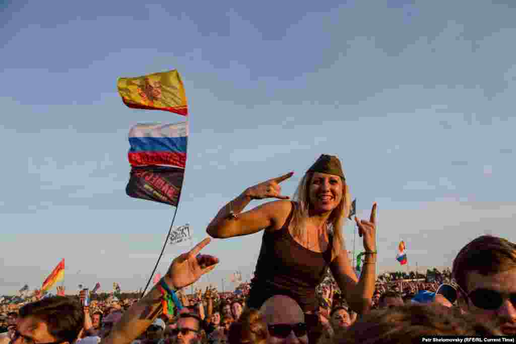 Flags fly behind a fan wearing a Soviet-era military cap.