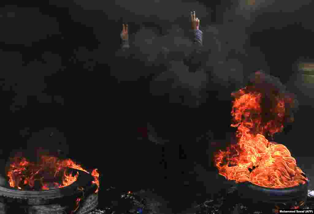 An Iraqi anti-government demonstrator gestures as he stands next to burning tires in the Shi&#39;ite Muslim shrine city of Karbala, south of Baghdad.&nbsp;