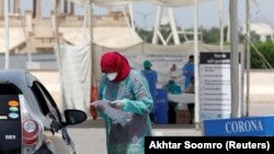 A health worker wearing a protective face mask takes someone's medical history at the drive-through screening and testing facility for coronavirus in Karachi on April 7. 