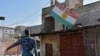 An Iraqi fighter loyal to the federal government carriesd away a sheet metal sign painted with the colours of the Kurdish flag from a building in the region of Altun Kupri, about 50 kilometres (30 miles) from Arbil, capital of autonomous Iraqi Kurdistan,