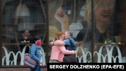زن و مردی در پایتخت اوکراین در حال بوسیدن یکدیگر، در حالی که زنی دیگر با ماسک از کنار آن‌ها عبور می‌کند. اوکراین یکی از بالاترین نرخ ابتلا به کرونا را دارد.