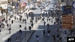 Regime loyalists throw stones toward antigovernment protesters in Sanaa.