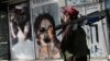 A Taliban fighter walks past a beauty salon with images of women defaced using spray paint in Kabul on August 18, days after the militant group seized the Afghan capital. 