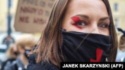 Žena na protestima u Varšavi nosi masku s usvojenim simbolom crvene munje (28. oktobar 2020.)