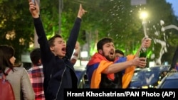 ARMENIA -- A man covered with a national flag waves an opened bottle of a sparkling wine celebrating Armenian Prime Minister's Serzh Sarkisian's resignation in Republic Square in Yerevan, April 23, 2018