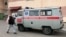 Belarus - April 10. 2020, a town of Dokšycy (Dokshytsy), Viciebskaja voblasc, a patient wearing mask is passing by the local hospital and an emergency car