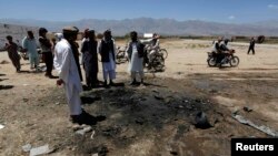 FILE: Afghan villagers stand at the site of an attack in Parwan Province in July.