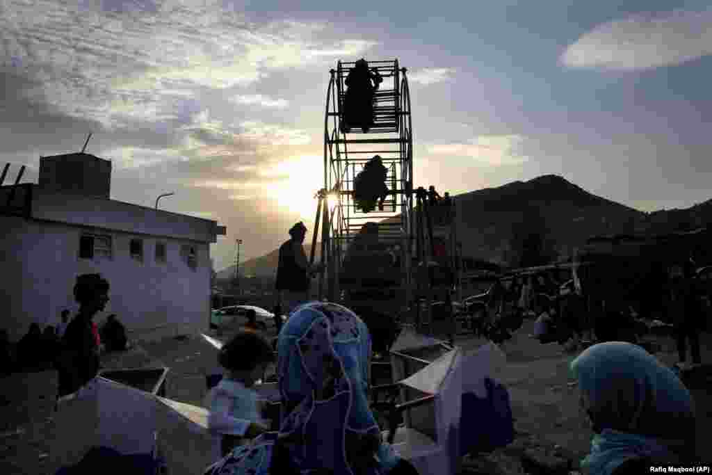 Children ride on a manual Ferris wheel outside the Kart-e Sakhi shrine in the Afghan capital, Kabul. (AP/Rafiq Maqbool)