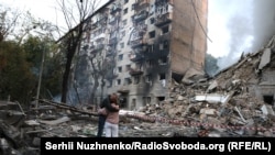 Подружжя біля зруйнованого внаслідок російського ракетного обстрілу будинку у Києві. Під завалами їхній син. Пізніше рятувальники знайдуть його тіло. Київ, 17 червня 2025 року.