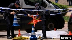 Spanish police officers work near the body of Andriy Portnov, a Ukrainian lawyer who was shot and killed by unidentified gunmen outside a school in Madrid on May 21.