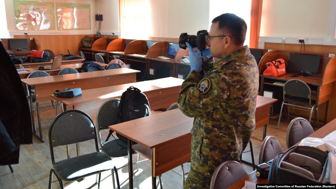 An investigator take pictures in a college classroom after a student shot and killed a fellow student and wounded three others before committing suicide in Blagoveshchensk on November 14.