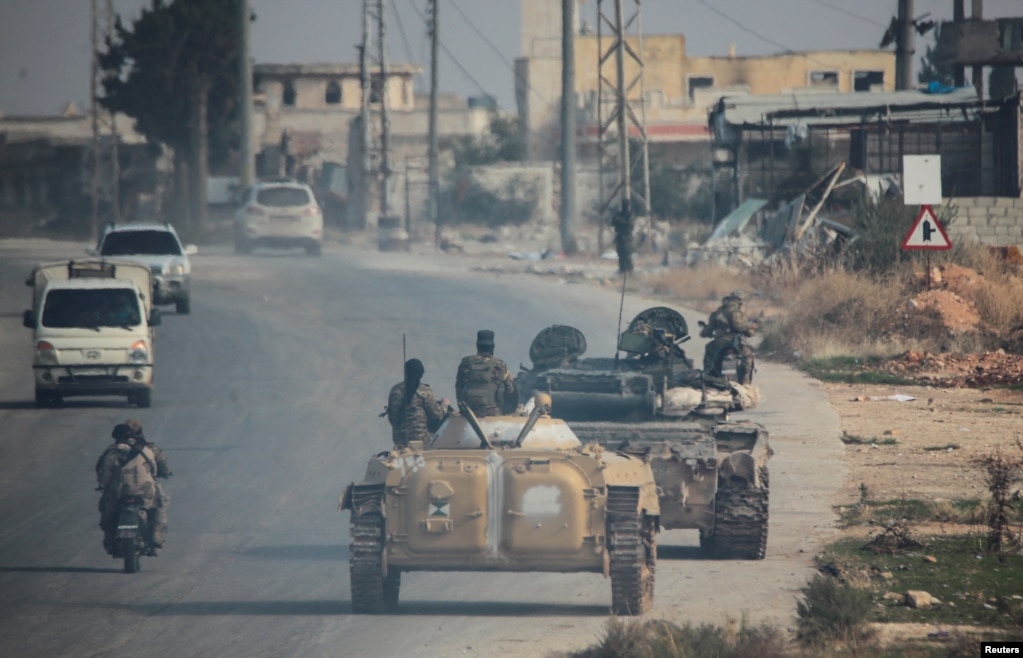 Hayat Tahrir al-Sham fighters drive along a street in Aleppo on November 29.