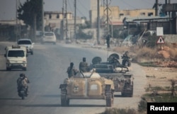 Rebels led by the Islamist militant group Hayat Tahrir al-Sham drive along a street in Rashideen, Syria, on November 29.