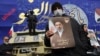A man holds a picture of Iran's new supreme leader, Mojtaba Khamenei, at a funeral ceremony in Tehran on March 11 for Iranian military commanders killed in strikes.