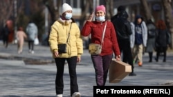 Женщины в защитных масках идут по улице Алматы. 18 марта 2021 года.
