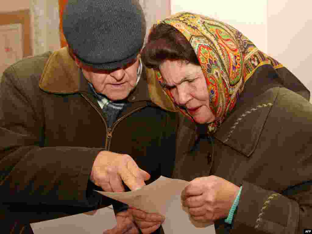 An elderly Ukrainian couple studies the ballot at a polling station in Chop, 800 kilometers west of Kyiv.