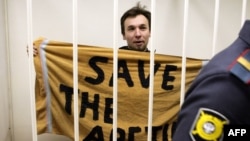 Polish Greenpeace International activist Tomasz Dziemianczuk, who left Russia on December 29, displays a "Save The Arctic" banner made from a towel during his detention hearing in St. Petersburg in mid-November.