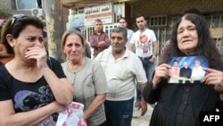 An Iraqi Christian woman (right) holds a picture of her son, who was killed in the October 31 church attack.