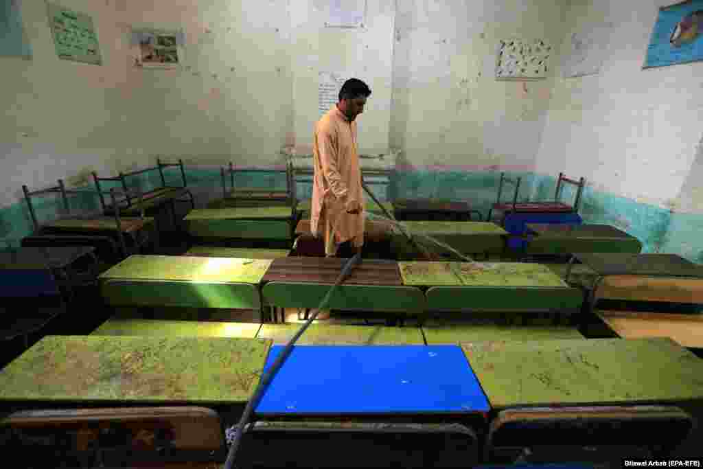 Рабочий убирает класс в школьном здании после того, как все учебные заведения закрылись в Пешаваре, Пакистан, на фоне увеличения случаев COVID-19