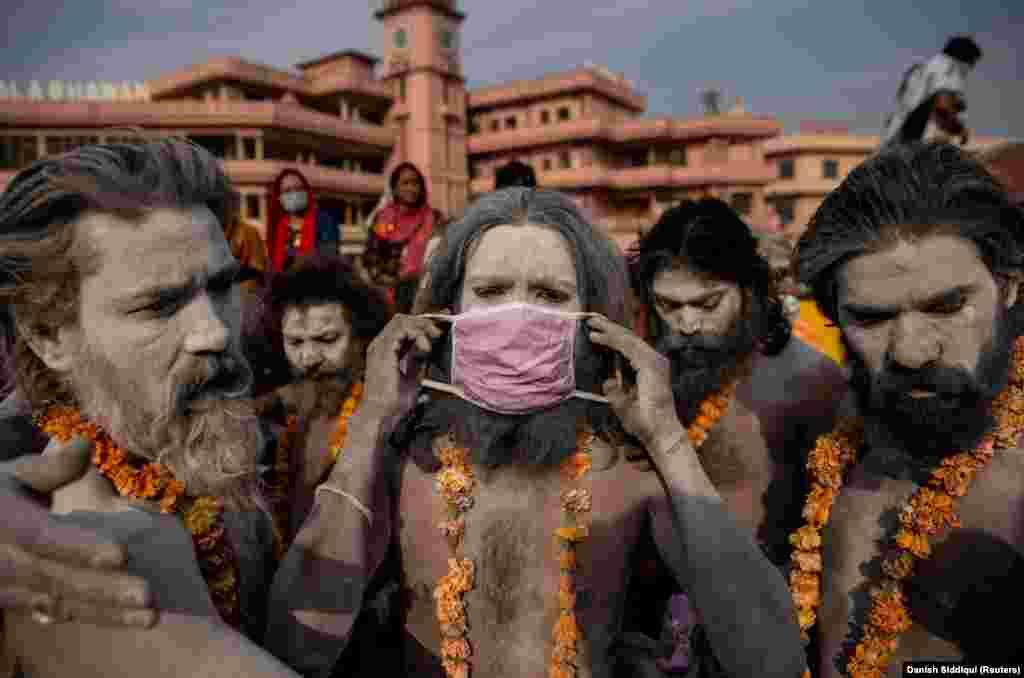 Egy Naga Szadu, azaz egy hindu szent ember maszkot vesz, mielőtt megmártózna a Gangesz folyóban.