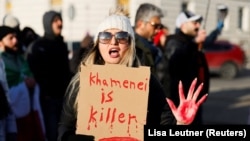 Участница митинга в поддержку протестов в Иране держит плакат с надписью "Хаменеи – убийца", Вена, Австрия, 18 января 2026 года