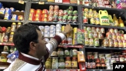 A vendor arranges canned products on a shelf at a grocery store in Tehran on December 19, as the Iranian government began to implement its controversial plan of scrapping subsidies on energy and food products as part of reforms that had been in the pipeli