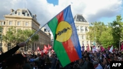 Un protestatar flutură steagul Kanak și Frontul Socialist de Eliberare Națională (FLNKS) în timpul unei demonstrații de susținere a poporului kanak la Place de la Republique din Paris, pe 16 mai 2024.