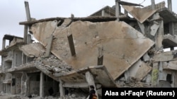 A student walks past rubble of damaged buildings in a rebel-held area in the city of Deraa, Syria January 25, 2018.