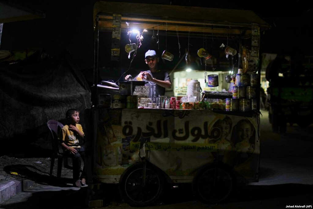Një djalë palestinez duke shikuar një shitës ambulant teksa po piqte misër.