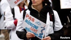 Un medic francez protestează la Paris, la data de 5 ianuarie. Medicul ține o pancartă pe care scrie „Nici un tratament fără medici”